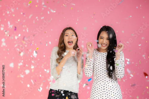 Portrait of two lovely cute asian women in christmas hats looking at camera isolated over pink background.Attractive asian woman smile in christmas, new year, valentine day, birthday .