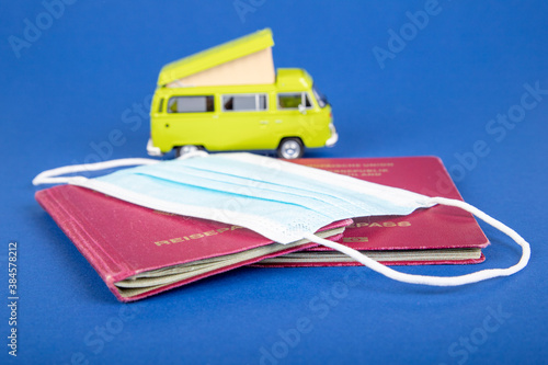 two German passports under a face mask, in the background a toy mobile home photo