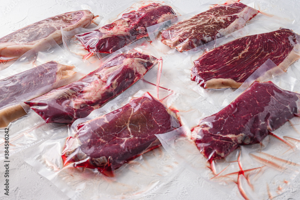 Set  of  vacuum packed organic raw beef steaks  alternative cuts over white background, side view.