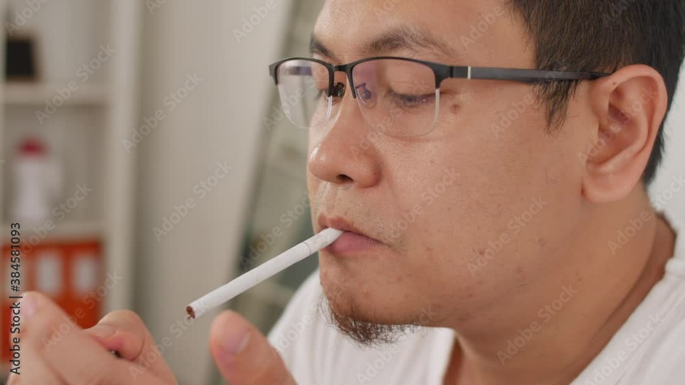 Asian man lights a cigarette and smoking, close up portrait of a smoker