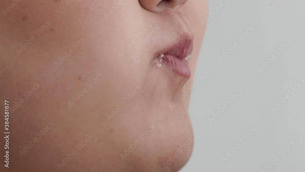 Close up of the mouth of a plump young woman who takes a bite and chaos a piece of hamburger with gusto. The concept is fast food. Close up of the mouth of a plump young woman who takes a bite and chaos a piece of hamburger with gusto. The concept is fast food.