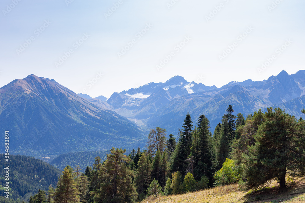 Mountain peak snow landscape against a blue sky in the Republic of Karachay-Cherkessia, Russia. Wonderful evergreen forest and ridges Mountain peak snow landscape against a blue sky in the Republic of Karachay-Cherkessia, Russia. Wonderful evergreen forest and ridges