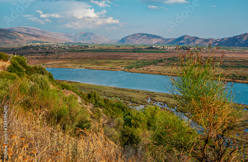 Beautiful summer landscape with blue river and valley in Albanian mountains, covered with dry grass and green bushes