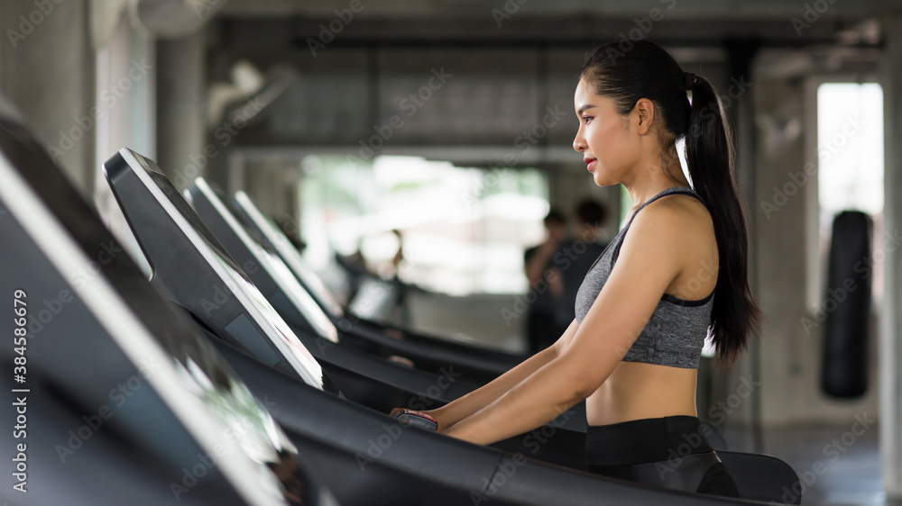 Asian attractive sporty woman walk cardio training on treadmills to warm up before running in fitness gym with copy space for text. Bodybuilding and healthy lifestyle concept.