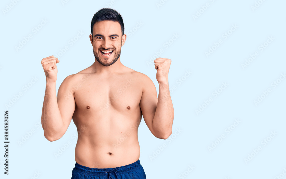 Fototapeta premium Young handsome man wearing swimwear screaming proud, celebrating victory and success very excited with raised arms