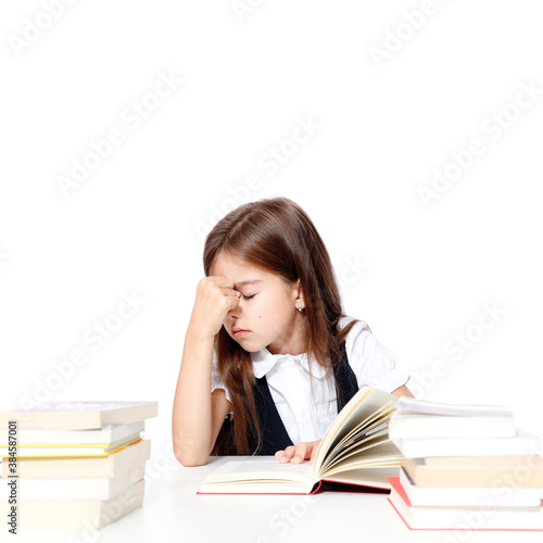 Tired little child girl sleeping on the desk at school.