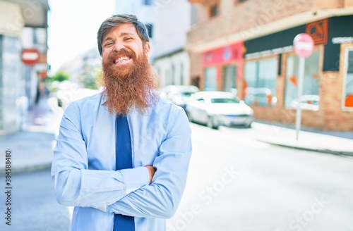 Young handsome redhead businessman wearing elegant clothes smiling happy. Standing with smile on face at street of city.