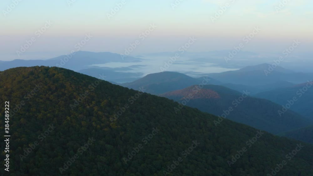 An aerial shot (dolly in) of the summit of Mt. Pleasant and surrounding mountains at sunrise, located in the Mount Pleasant Special Management Area of the George Washington National Forest, Virginia. An aerial shot (dolly in) of the summit of Mt. Pleasant and surrounding mountains at sunrise, located in the Mount Pleasant Special Management Area of the George Washington National Forest, Virginia.