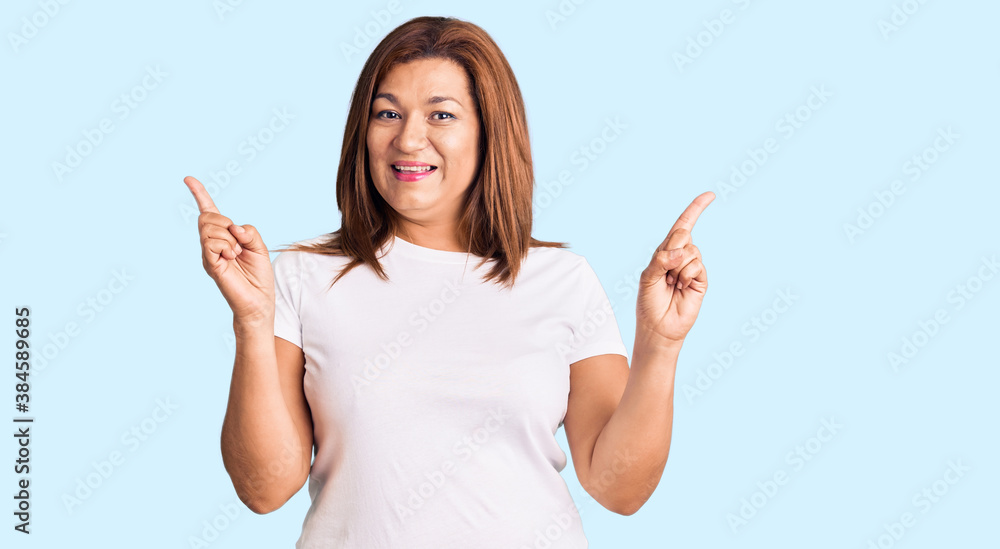 Middle age latin woman wearing casual white tshirt smiling confident pointing with fingers to different directions. copy space for advertisement Middle age latin woman wearing casual white tshirt smiling confident pointing with fingers to different directions. copy space for advertisement