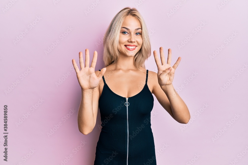 Fototapeta premium Beautiful caucasian blonde girl wearing sexy party dress showing and pointing up with fingers number nine while smiling confident and happy.