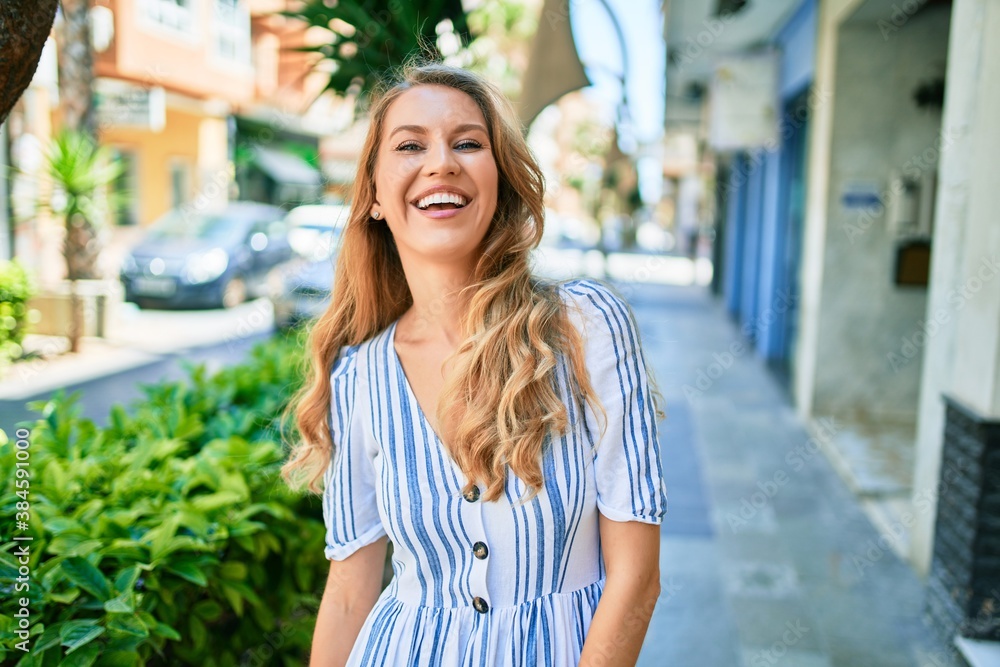 Naklejka premium Young beautiful caucasian woman with blond hair smiling happy and cheerful walking on sunny day