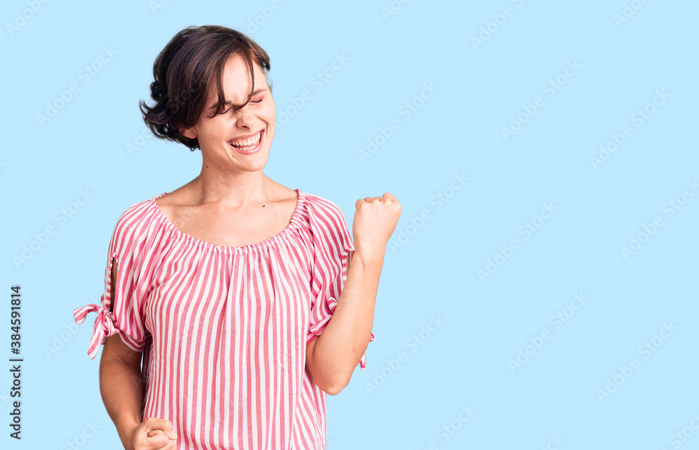 Beautiful young woman with short hair wearing casual summer clothes celebrating surprised and amazed for success with arms raised and eyes closed. winner concept. Beautiful young woman with short hair wearing casual summer clothes celebrating surprised and amazed for success with arms raised and eyes closed. winner concept.