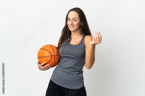Young woman playing basketball over isolated white background making money gesture