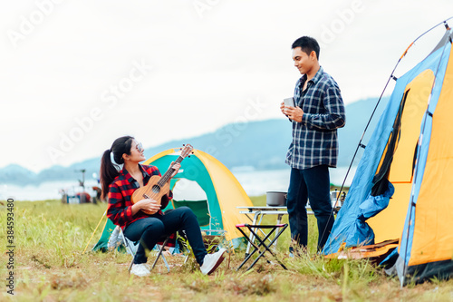Group of friends camping and they are sitting playing guitar. Camp and music guitar concept.
