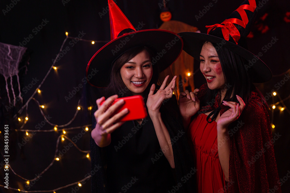 Obraz premium Women wear witch costumes for Halloween. Young women are using mobile phones. Halloween festival