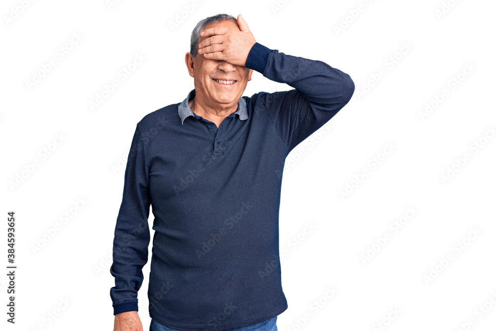 Senior handsome man wearing casual polo smiling and laughing with hand on face covering eyes for surprise. blind concept. Senior handsome man wearing casual polo smiling and laughing with hand on face covering eyes for surprise. blind concept.