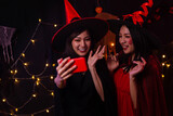 Women wear witch costumes for Halloween. Young women are using mobile phones. Halloween festival