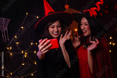 Women wear witch costumes for Halloween. Young women are using mobile phones. Halloween festival