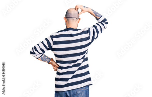 Young handsome man wearing burglar mask backwards thinking about doubt with hand on head
