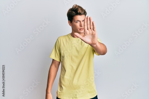 Handsome caucasian man wearing casual clothes doing stop sing with palm of the hand. warning expression with negative and serious gesture on the face.