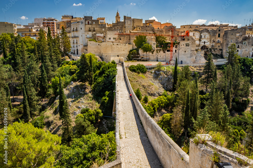 Gravina in Puglia, Italy. The stone bridge, ancient aqueduct and viaduct. On the other side of the valley where the Gravina stream flows, the skyline of the city with its houses and palaces.