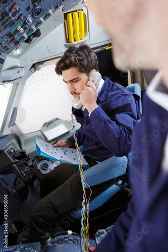 technician holding telephone in aircraft cockpit