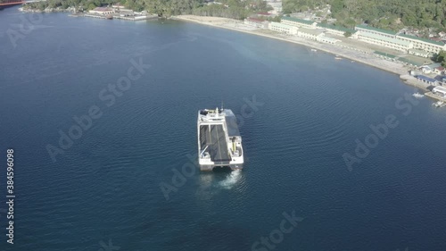 Local Passenger Fastcat Ferry Boat At The Calm Blue Waters Preparing To Leave Liloan Port in Southern Leyte, Philippines. - Aerial Drone Arc Shot photo