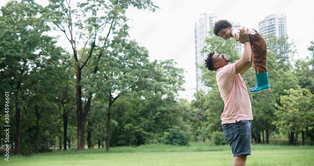 African father spends time and have fun together with his son. Young dad with beard and mustache carried his little boy in the air at garden green park on weekend