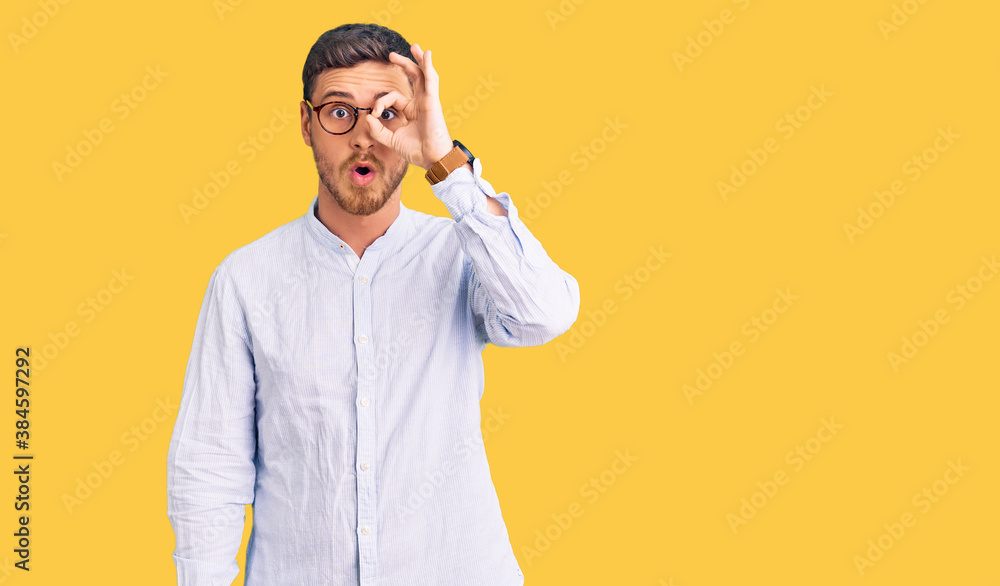 Handsome young man with bear wearing elegant business shirt and glasses doing ok gesture shocked with surprised face, eye looking through fingers. unbelieving expression. Handsome young man with bear wearing elegant business shirt and glasses doing ok gesture shocked with surprised face, eye looking through fingers. unbelieving expression.