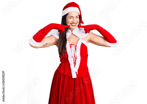 Young beautiful caucasian woman wearing santa claus costume smiling cheerful showing and pointing with fingers teeth and mouth. dental health concept.