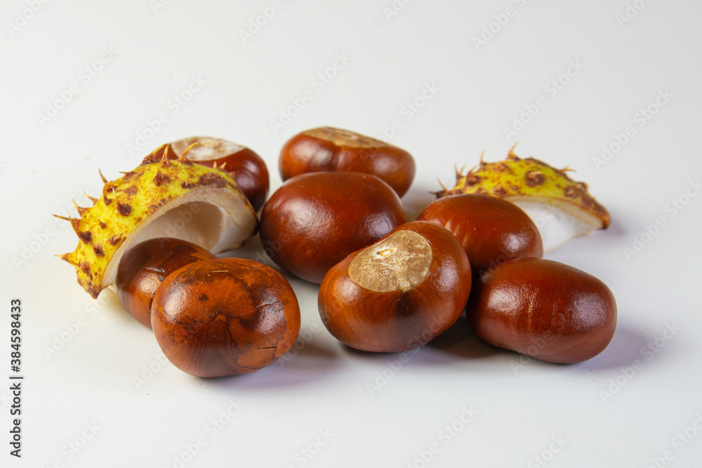 A few brown chestnuts with green peels isolated on white background A few brown chestnuts with green peels isolated on white background