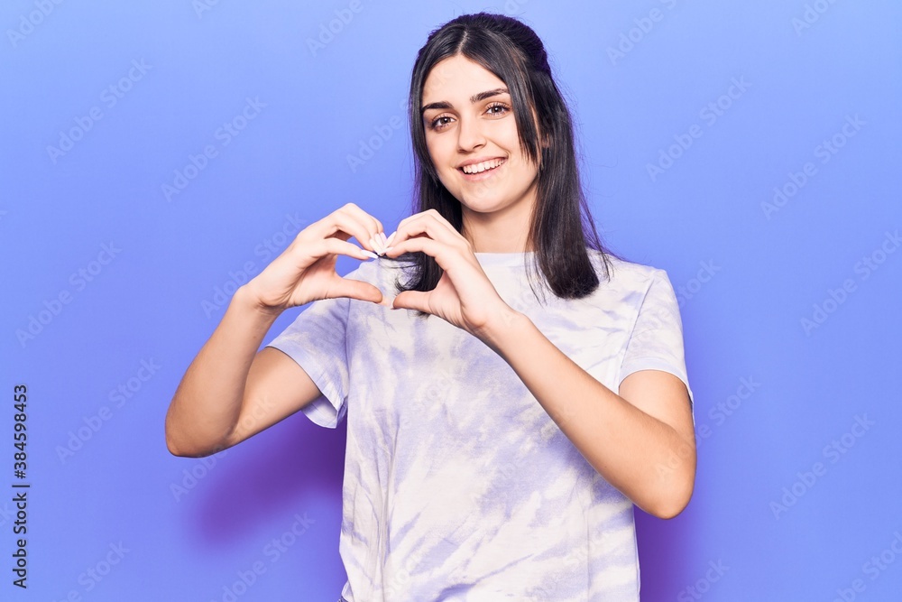 Young beautiful girl wearing casual t shirt smiling in love doing heart symbol shape with hands. romantic concept.