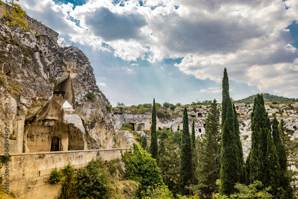 Gravina in Puglia, Italy. The ancient cave church of San Michele delle Grotte, carved into the rock. The Botromagno archaeological park. The tips of the cypresses emerge from the valley below.
