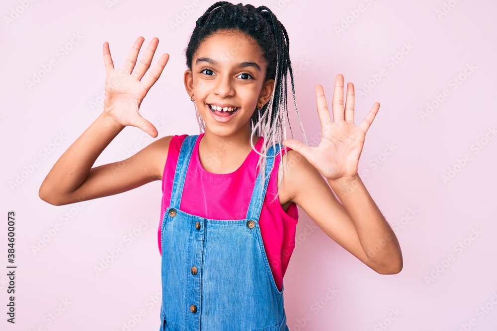Young african american girl child with braids wearing casual clothes over pink background showing and pointing up with fingers number ten while smiling confident and happy. Young african american girl child with braids wearing casual clothes over pink background showing and pointing up with fingers number ten while smiling confident and happy.