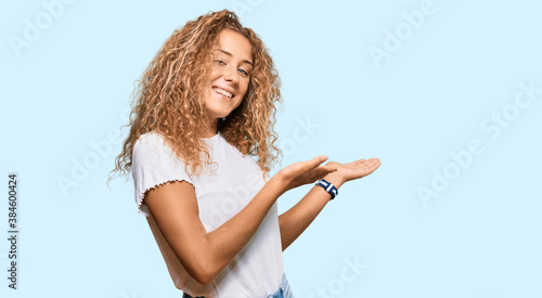 Obraz na plátně Beautiful caucasian teenager girl wearing casual white tshirt inviting to enter