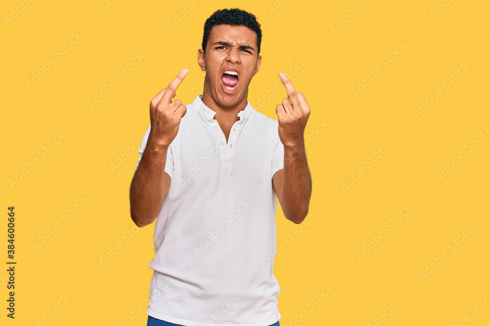 Young arab man wearing casual clothes showing middle finger doing fuck you bad expression, provocation and rude attitude. screaming excited Young arab man wearing casual clothes showing middle finger doing fuck you bad expression, provocation and rude attitude. screaming excited