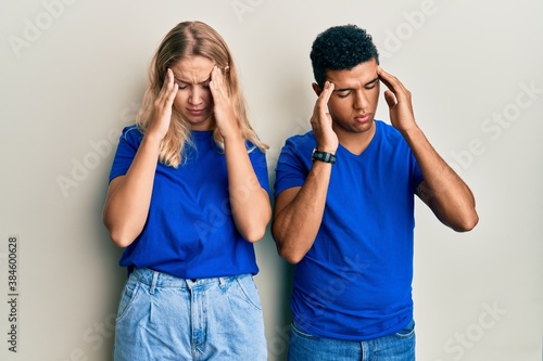 Young interracial couple wearing casual clothes with hand on head, headache because stress. suffering migraine.