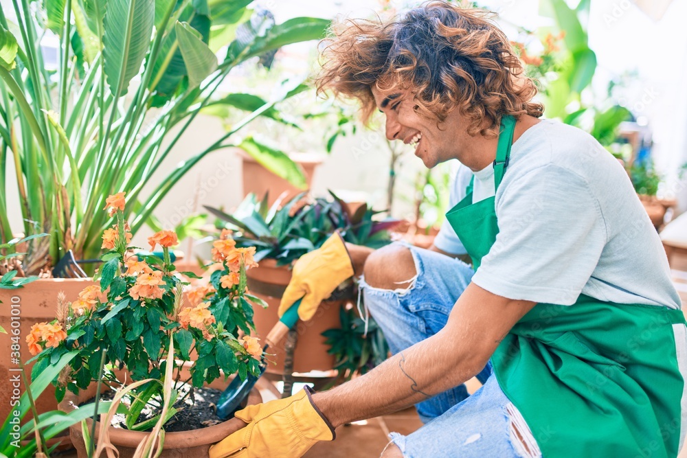 Young hispanic gardener smiling happy caring plants using garden shovel at terrace Young hispanic gardener smiling happy caring plants using garden shovel at terrace