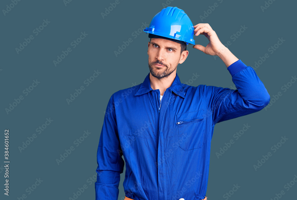 Young handsome man wearing worker uniform and hardhat doing stop sing with palm of the hand. warning expression with negative and serious gesture on the face.