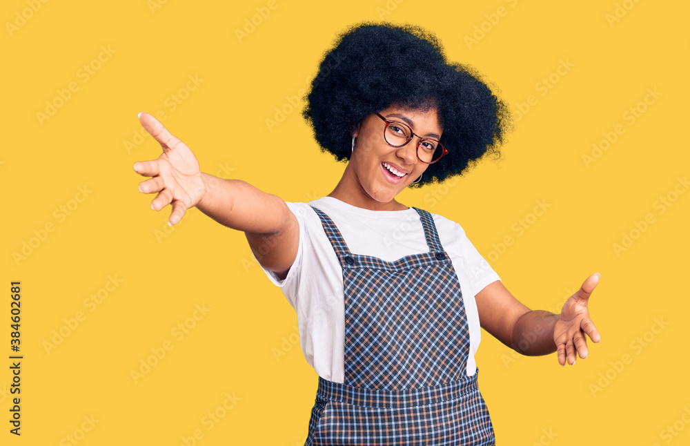 Young african american girl wearing casual clothes looking at the camera smiling with open arms for hug. cheerful expression embracing happiness. Young african american girl wearing casual clothes looking at the camera smiling with open arms for hug. cheerful expression embracing happiness.