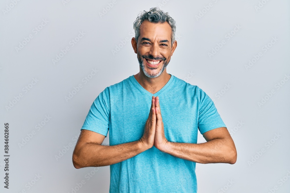 Middle age grey-haired man wearing casual clothes praying with hands together asking for forgiveness smiling confident. Middle age grey-haired man wearing casual clothes praying with hands together asking for forgiveness smiling confident.