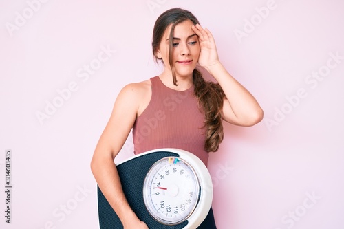 Obraz na plátně Beautiful young caucasian woman holding weight machine to balance weight loss st