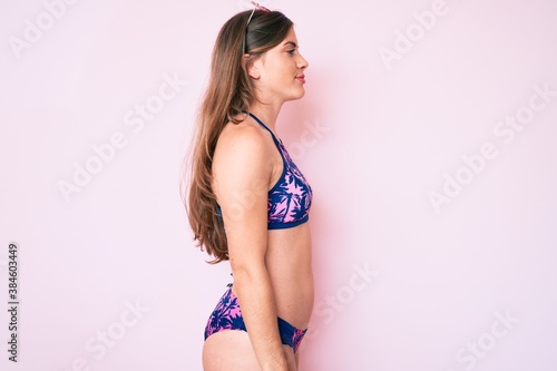 Beautiful young caucasian woman wearing bikini and sunglasses looking to side, relax profile pose with natural face with confident smile. © Krakenimages.com