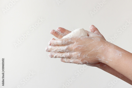 Two lathered hands hold soap between their palms on a white background. The concept of the need to wash hands to prevent diseases
