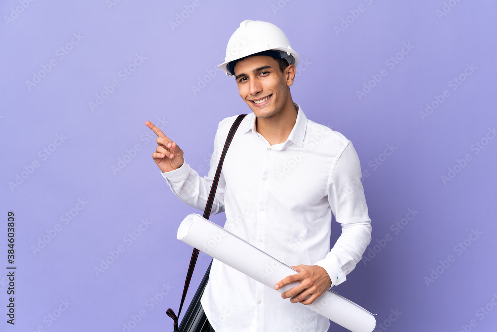 Young architect man isolated on background pointing finger to the side Young architect man isolated on background pointing finger to the side