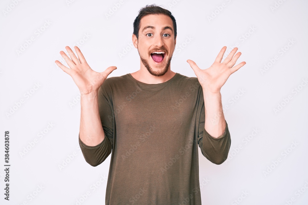 Young handsome man wearing casual clothes celebrating crazy and amazed for success with arms raised and open eyes screaming excited. winner concept Young handsome man wearing casual clothes celebrating crazy and amazed for success with arms raised and open eyes screaming excited. winner concept