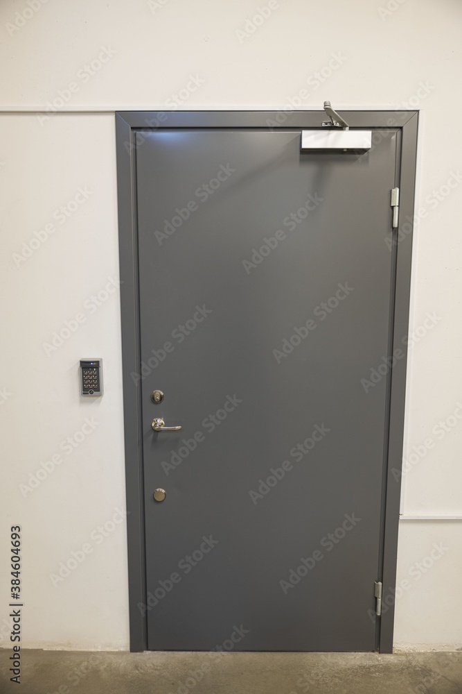 Close up view of grey metal door with digital code lockand extra heavy aluminum commercial door closer. Security concept. Close up view of grey metal door with digital code lockand extra heavy aluminum commercial door closer. Security concept.