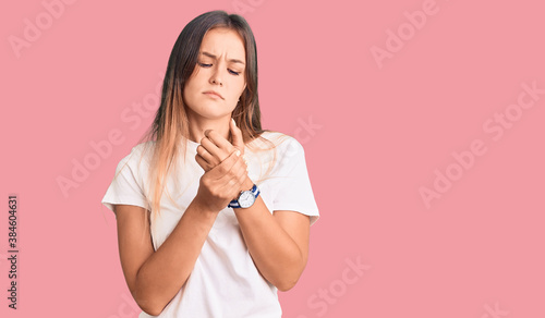 Beautiful caucasian woman wearing casual white tshirt suffering pain on hands and fingers, arthritis inflammation