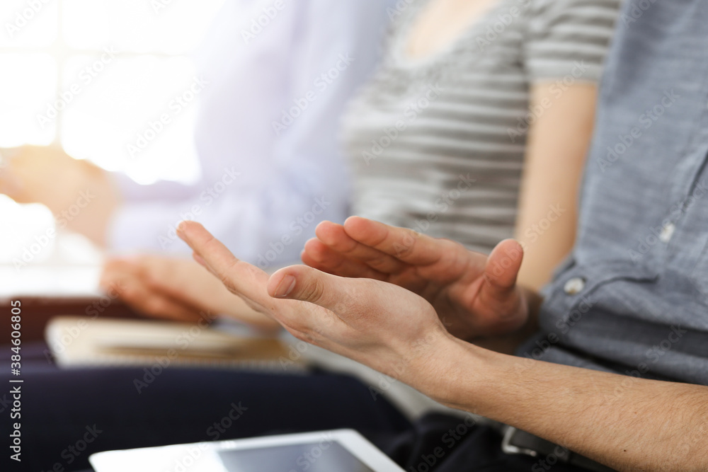 Business people clapping at meeting or conference, close-up of hands. Group of unknown businessmen and women in sunny office