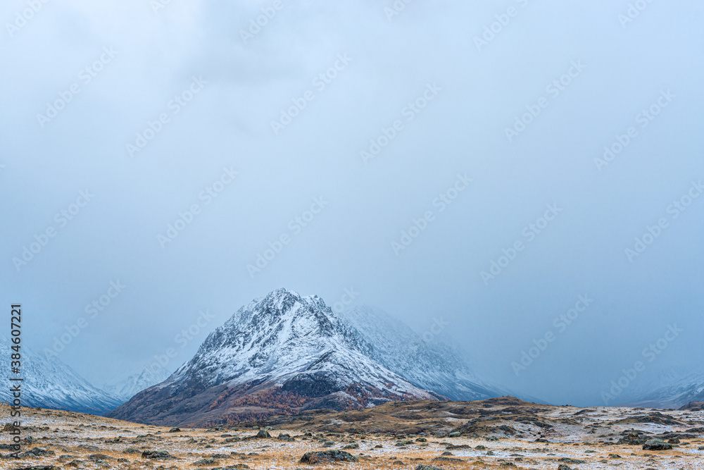 panoramic view of picturesque snowy mountains tops in foggy morning 
